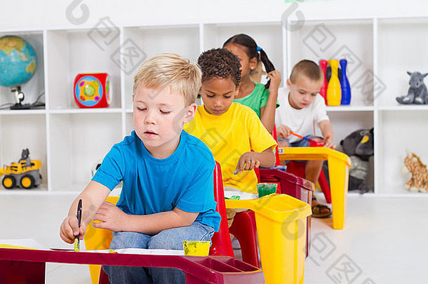 一组四个学龄前儿童在教室里画画