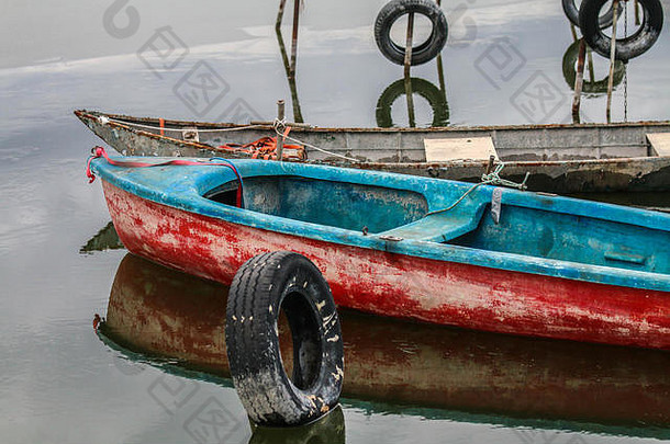 漂浮在水面上的古老的木制小渔船。他们站在小码头上。