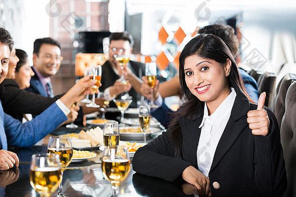 1名女商人在餐厅商务聚会上与合作伙伴竖起大拇指