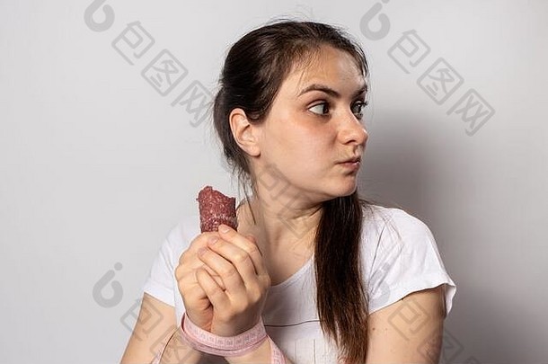 一个女人吃烟熏香肠，咬得很厉害。减肥时饮食中断。拒绝适当的营养、有害的高热量食物。