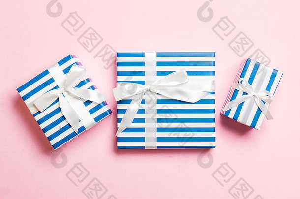在纸上用粉红色背景上的白色丝带包装圣诞或其他节日手工礼品。礼品盒，彩台礼品装饰，t