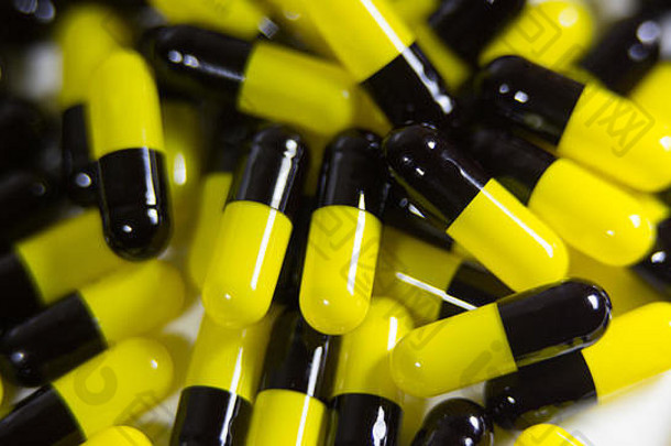 许多黑色和黄色的药丸和药片的特写镜头被隔离在白色背景上。处方药。<strong>药物</strong>、止痛药和<strong>药物滥用</strong>