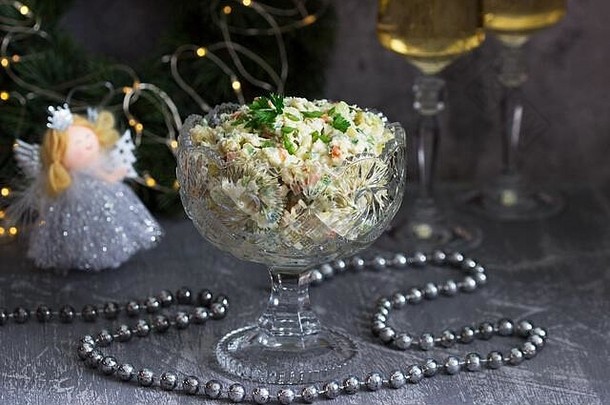 传统节日色拉奥利维尔装在水晶花瓶中，配以白葡萄酒作为圣诞装饰的背景。