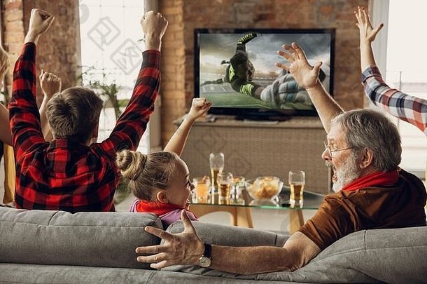 胜利兴奋、快乐的一家人在家的沙发上看足球、足球比赛、冠<strong>军</strong>赛。球迷们为最受欢<strong>迎</strong>的国家队欢呼。女儿，爸爸和爷爷。<strong>运</strong>动、电视、娱乐。