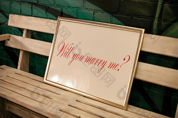 带框架和铭文的标签“你们愿意嫁给我吗？”放在木凳上。闭合。