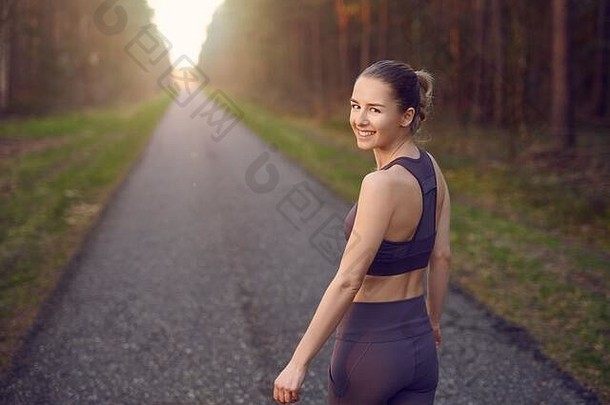 适合<strong>运动</strong>年轻的女人慢跑日出直后退路森林树发光太阳结束把微笑