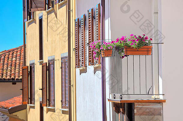 在意大利拉莫拉镇，一座典型的意大利房子的阳台上摆放着花盆，房子有木制百叶窗和瓷砖屋顶。