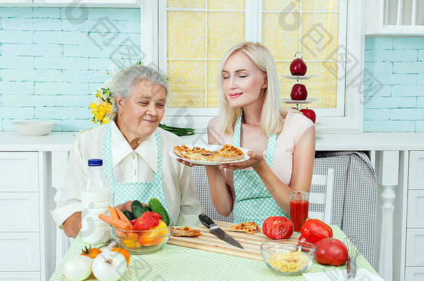 祖母女人闻了闻新鲜煮熟的披萨家庭主妇