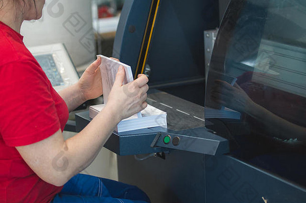在印刷设备前手持一堆纸的女工人的手