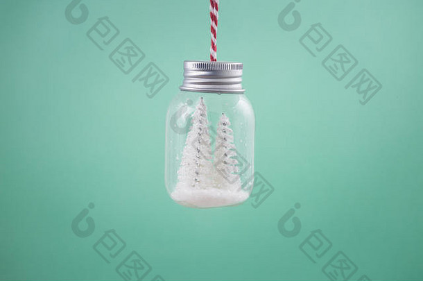 透明装饰装饰罐的特写镜头，里面有白色圣诞树和雪。