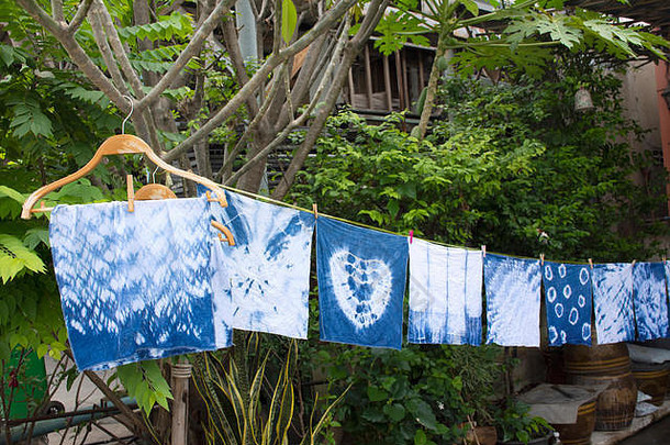 手帕、扎染、扎染、扎染、靛蓝色或毛姆色，并在泰尔省农塔布里室外花园的阳光下晾干衣服