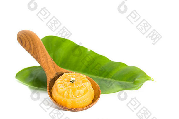甜黄色甜点皇家泰国料理，绿色叶子和木勺装饰在纯白背景上