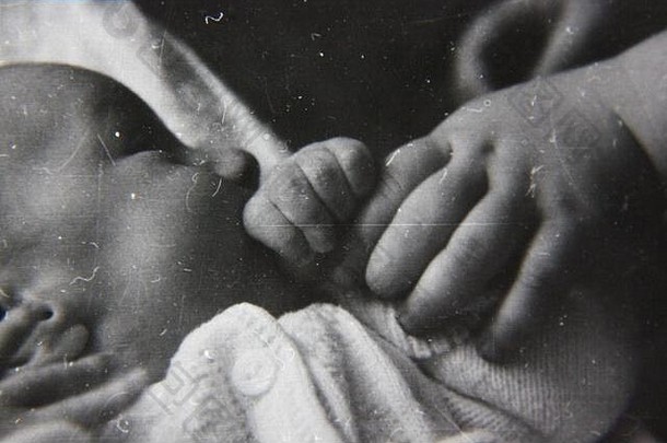 70年代经典黑白照片，拍摄的是一个年长的兄弟姐妹牵着一个新生婴儿的小手。