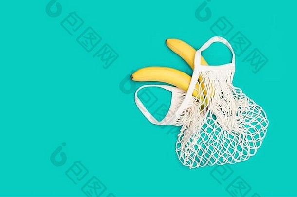 两个明亮的香蕉装在环保袋中，背景为<strong>薄荷色</strong>。零废物概念，无塑料，环保购物，素食主义者