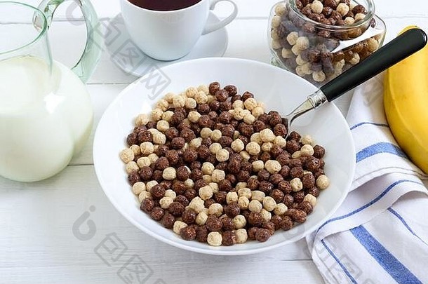 白色木质背景上的全麦巧克力和牛奶球、水果、茶和牛奶。健康谷物早餐。婴儿早餐。吃婴儿。平衡d