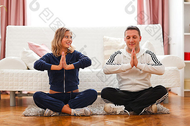 年轻孕妇和丈夫在家做瑜伽