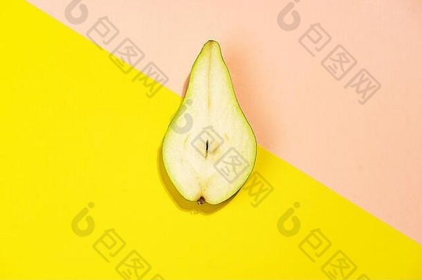 在明亮的黄色和柔和的粉红色背景上用半个梨做成的创意图案。水果最小概念。俯视图，平放，特写。