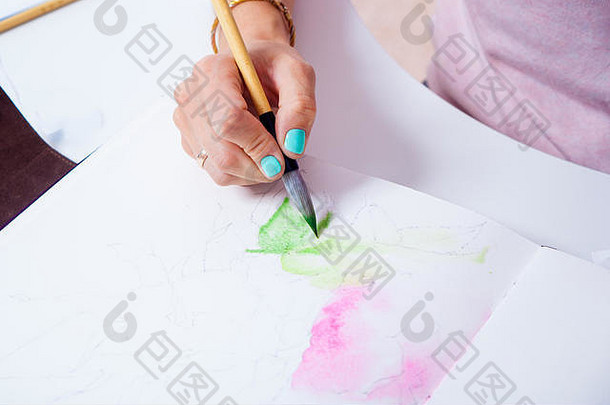 一位女艺术家的特写镜头在一本<strong>画册</strong>中用薄木笔和水彩画画了一朵粉红色的牡丹花，<strong>画册</strong>的背景是白色的