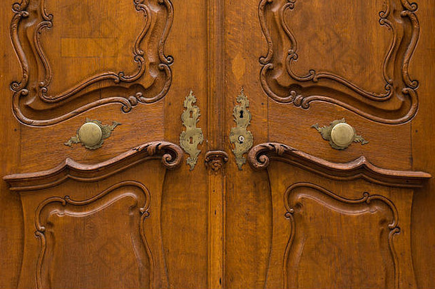 雕刻精美的木门，带有金属门把手和装饰过的钥匙孔。