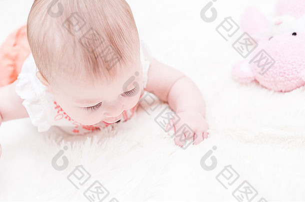 可爱的小女孩在白色毯子上玩耍。