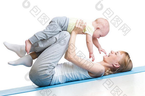 年轻的成年妇女抱着她的小儿子跪着做瑜伽健身操。白色的隔离带。