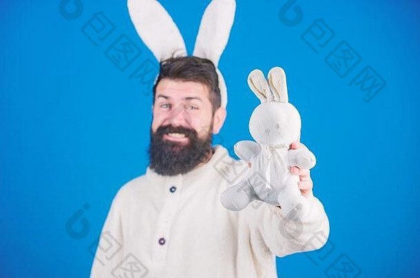 笑嘻嘻的大胡子男人戴着愚蠢的兔子<strong>耳朵</strong>。复活节象征概念。时髦可爱的兔子长<strong>耳朵</strong>蓝色背景。复活节兔子。有胡子和小胡子的有趣的兔子。参加庆祝活动。玩得开心。