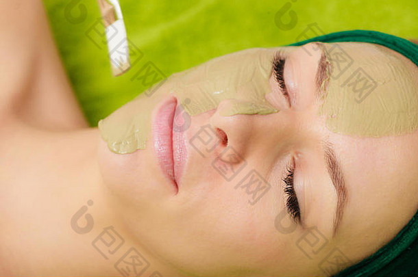 有人在女人脸上涂绿藻泥面膜。spa理念中的美容、放松、护肤、健康。
