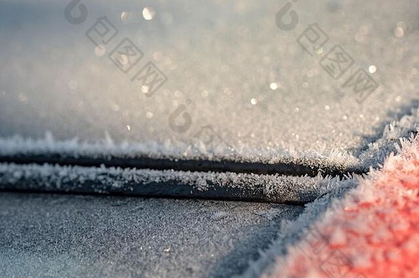 隆冬时节，一辆汽车的挡风玻璃和玻璃全景车顶上结霜严重，部分焦点较浅。