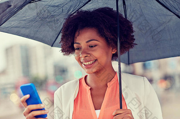 带着雨伞的女商人在智能手机上发短信