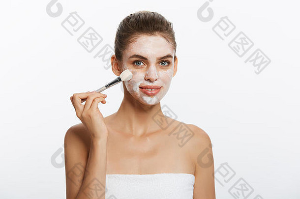 肖像美丽的女人用刷子涂上白色化妆泥<strong>面膜</strong>。隔离在白色背景上。美与健康的概念