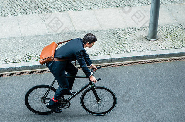 年轻的男人。穿业务西装骑实用程序自行车