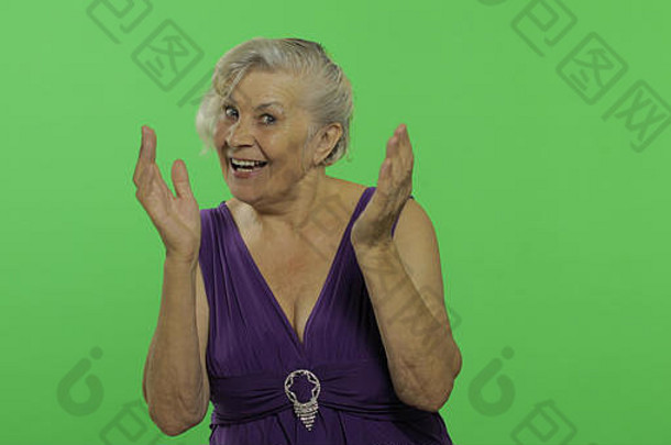 上了年纪的女人显示惊讶的是快乐微笑漂亮的快乐祖母紫色的衣服的地方标志文本浓度关键绿色屏幕背景
