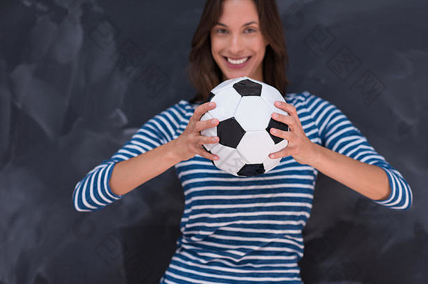 一名年轻女子手持足球在粉笔画板前的肖像
