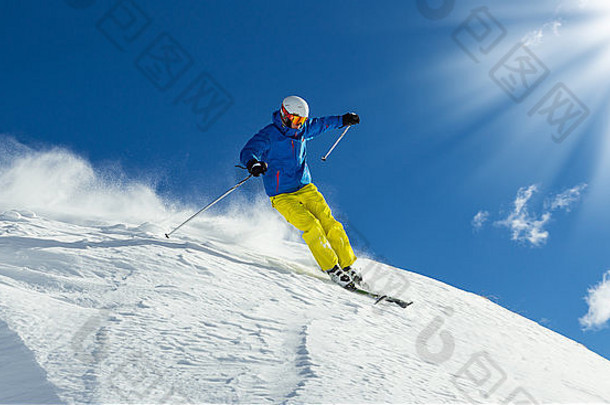 男子滑雪者在下坡免费滑雪时享受阳光和山景