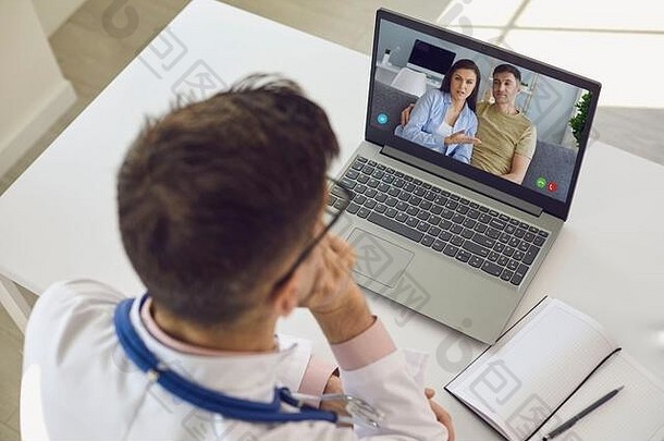 医生在线电话。肩视图医生治疗师心理学家在诊所办公室用笔记本电脑与夫妇视频聊天。