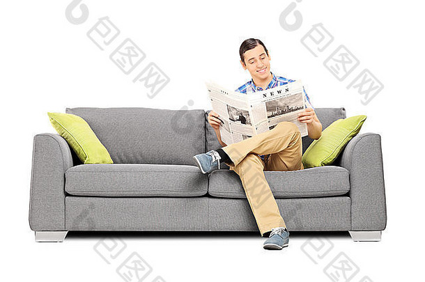 和平年轻的男人。阅读新闻坐着沙发孤立的白色背景