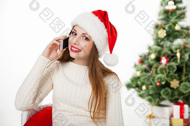 戴圣诞帽的女孩在圣诞树旁打电话