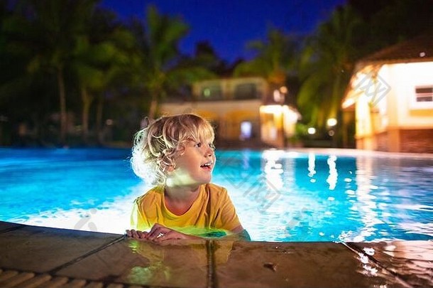 孩子们晚上在热带度假区的室外游泳池里玩耍。晚上在异国小岛上游泳。婴儿学潜水。孩子们在水里玩耍。海滩