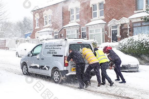 人们在大雪中帮助推着卡住的汽车