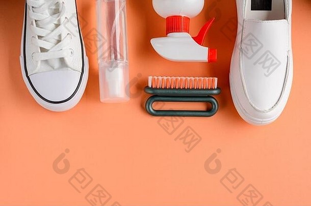 橙色背景上的运动鞋、刷子和清洁剂喷雾