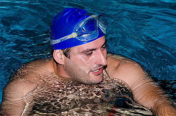 年轻的游泳运动员覆盖公共池蓝色的游泳帽