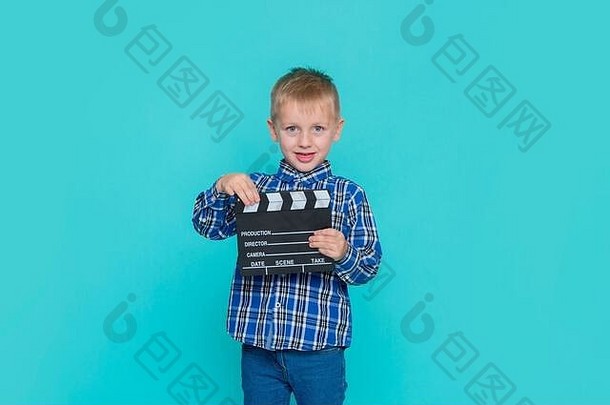 微笑的孩子拿着蓝色背景的电影隔板