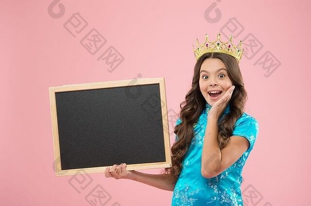 这就是感觉。快乐的公主拿着学校的黑板。戴皇冠的骄傲女孩回到了学校。促销或广告的空白板，空间。小孩子戴着舞会的王冠。学校的节日庆祝活动。