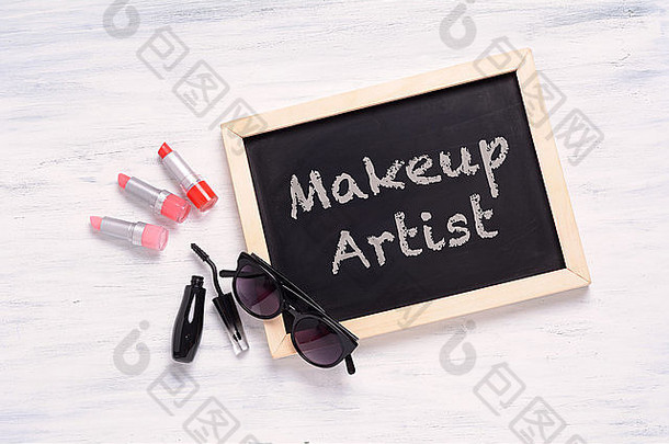 黑板化妆艺术家写化妆品产品白色木背景时尚化妆概念