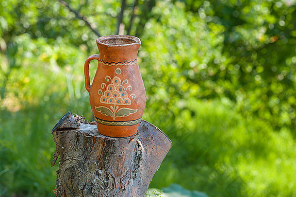 古代乌克兰传统陶罐，矗立在夏季花园的一棵砍树上