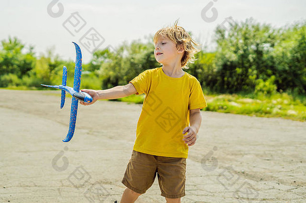 快乐的孩子在旧跑道背景下玩玩具飞机。带孩子旅行的概念