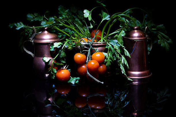 黑色背景上樱桃番茄和铜罐的组合