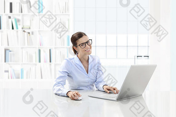 一位面带微笑的女士或一位在办公桌旁用电脑工作的职员，她戴着眼镜