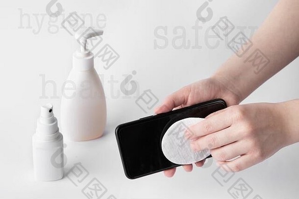 有人用棉垫擦拭黑色手机屏幕进行消毒。