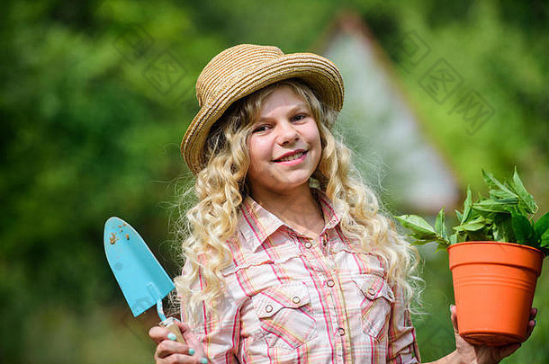儿童节快乐。戴帽子的孩子用肩胛骨小铲锄头。快乐微笑的园丁女孩。快乐的童年。农场女孩。种植植物。小孩拿着花盆。春天的乡村工作。